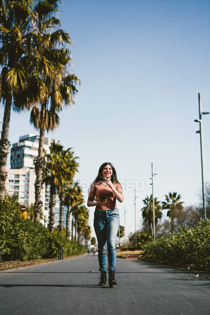 Adolescente caminando felizmente por las calles de la ciudad en un día soleado - foto de stock
