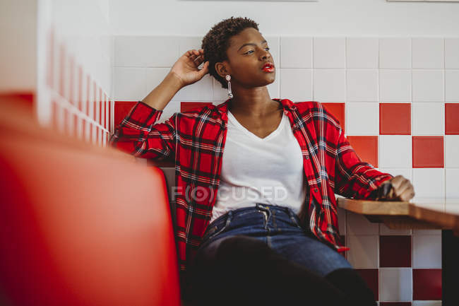 Confiante mulher afro-americana sentada à mesa no café e olhando para longe — Fotografia de Stock
