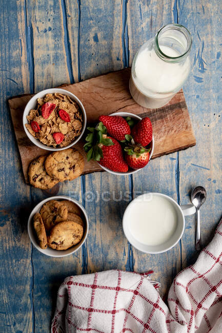 Стекло и бутылка молока и куча свежего печенья на деревянной доске возле салфетки — стоковое фото