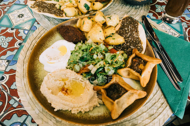 Von oben große Schüssel mit verschiedenen appetitlichen Speisen in der Nähe von Besteck auf Serviette am Tisch im Café — Stockfoto