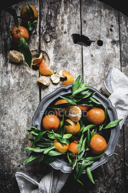 Fresh mandarins with leaves and platter on grey wooden table — Stock Photo