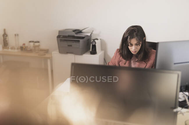 Concentré jeune femme à l'aide d'un ordinateur portable et assis à la table — Photo de stock