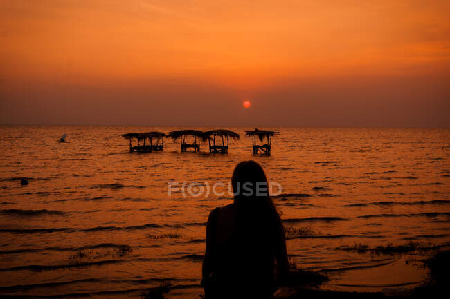 Donna vicino lavanderia in mare al tramonto — Foto stock