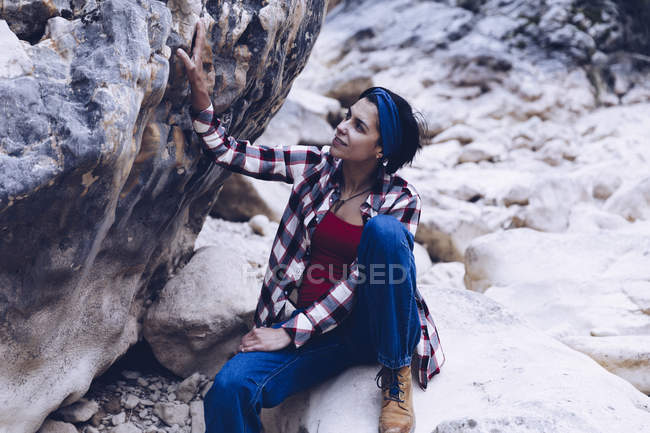 Dall'alto donna sorridente attraente che riposa su roccia su montagna — Foto stock