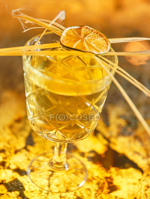 Closeup dried citrus and spices on top of small glass of tropical cocktail in bar — Stock Photo