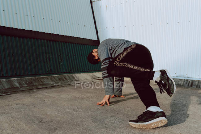 Хлопець танцює біля стіни сучасної будівлі на міській вулиці — стокове фото