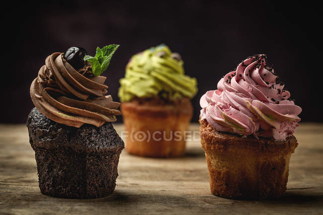 Deliciosos cupcakes caseiros no fundo embaçado rústico — Fotografia de Stock
