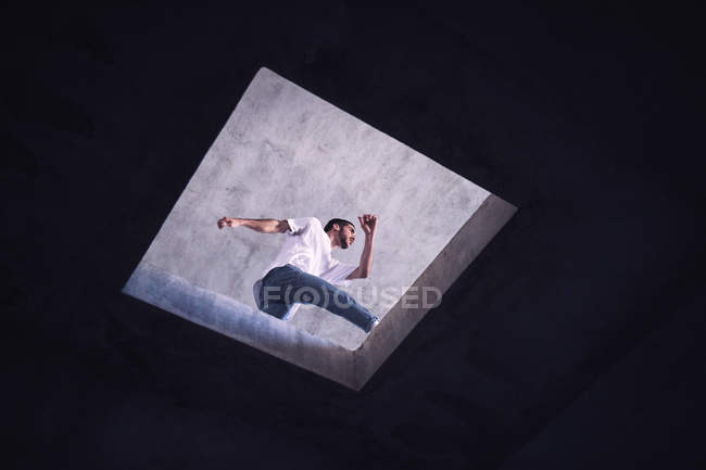 Young dancer jumping over hole in roof, low angle view — Stock Photo