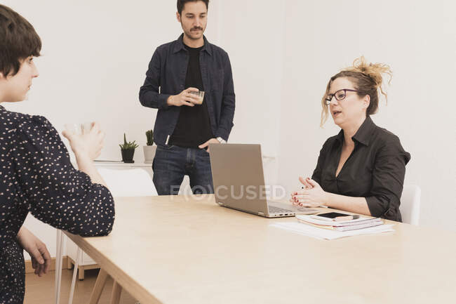 Concentré jeune homme près de dame naviguant sur ordinateur portable à la table dans le bureau — Photo de stock
