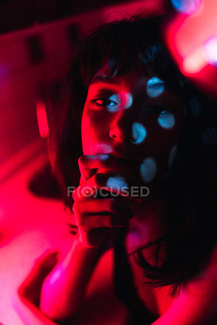 Sensual jovem morena mulher olhando para a câmera entre vermelhidão — Fotografia de Stock