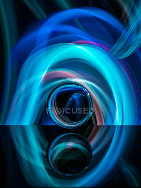 Кришталева куля на поверхні з відображенням біля абстрактних сяйв — стокове фото