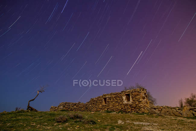 Long exposure of amazing sky with stars in evening and aged rock construction on hill — Stock Photo