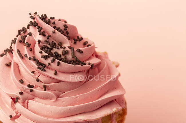 Primer plano de delicioso cupcake casero sobre fondo rosa - foto de stock