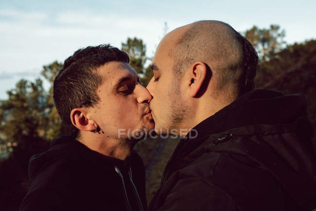 Closeup of homosexual couple kissing on path in nature — Stock Photo