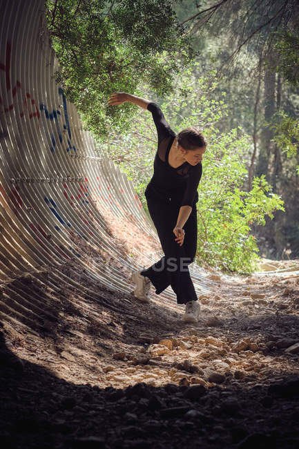 Bella giovane donna in abito nero danza balletto nella giornata di sole nella foresta incredibile — Foto stock