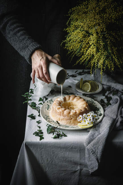 Coltivazione mano di cuoco irriconoscibile versando vetri sulla torta Bundt con limone — Foto stock
