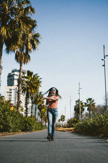 Adolescente marchant joyeusement dans les rues de la ville par une journée ensoleillée — Photo de stock