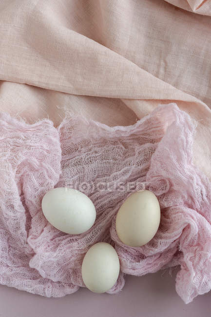 Oeufs blancs frais sur tissu rose — Photo de stock