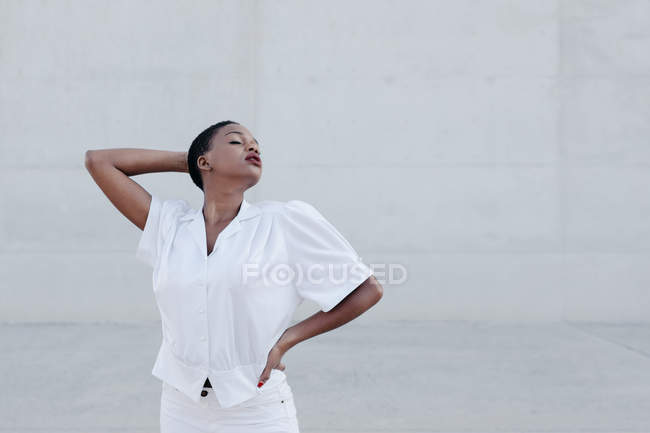 Moda sensual modelo de cabelos curtos em roupa branca posando contra a parede cinza — Fotografia de Stock