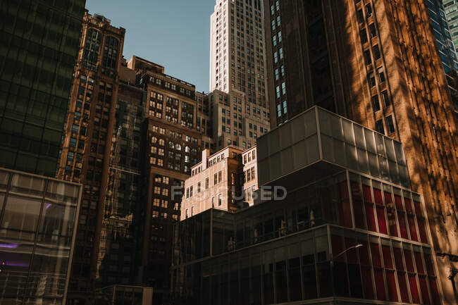 De abaixo do exterior de edifícios na densidade na rua da cidade de Nova Iorque na luz solar — Fotografia de Stock