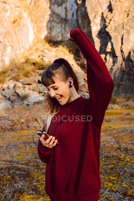 Young hipster woman with upped hand listening music with mobile phone and dancing in countryside — Stock Photo