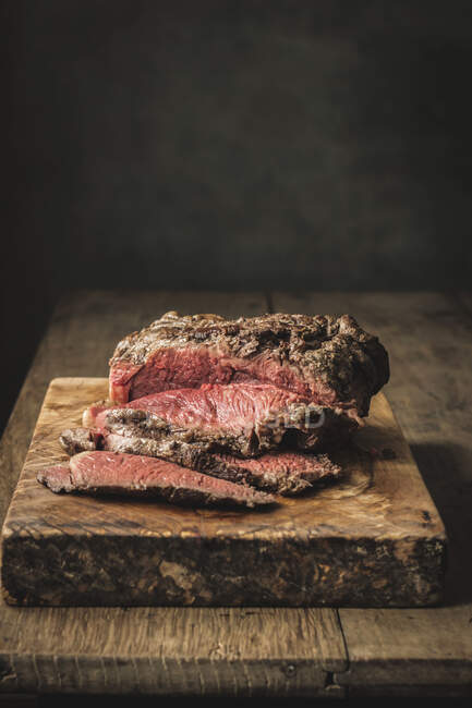 Juicy fresh cooked roast beef on rough cutting board on table — Stock Photo