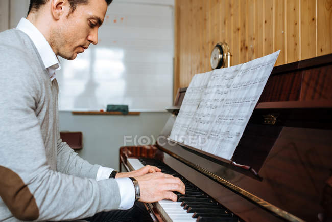 Bellissimo uomo che suona il pianoforte durante le prove in studio di registrazione
. — Foto stock
