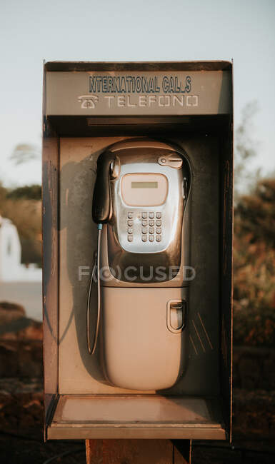 Telefone público desgastado para chamadas internacionais localizadas no campo no dia ensolarado — Fotografia de Stock
