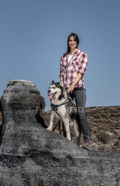 Smiling young woman standing with husky on deserted land in Tenerife, Canary Islands, Spain — Stock Photo