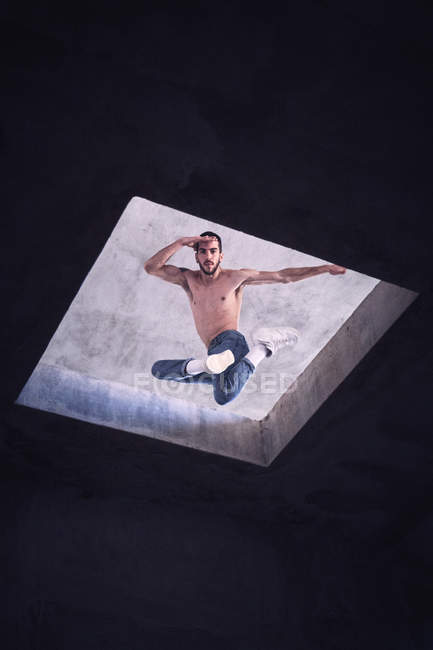 Молодой танцор прыгает через отверстие в крыше, вид с низкого угла — стоковое фото
