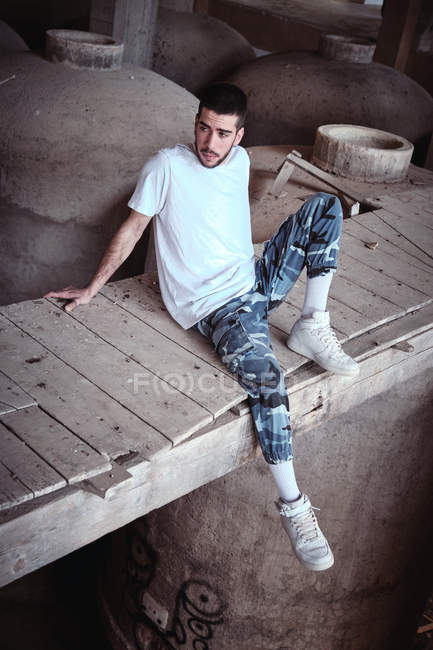 Homem sentado na ponte dentro do edifício velho, visão de alto ângulo — Fotografia de Stock