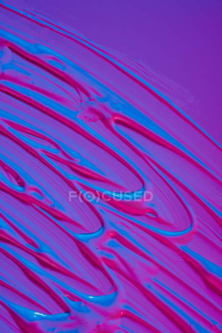 Pozzanghera di vernice acrilica al neon brillante diffusa su sfondo viola vivido — Foto stock
