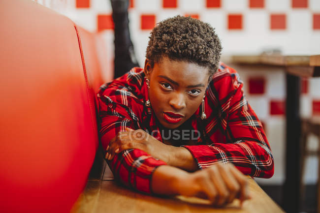 Впевнена афроамериканців жінка лежала на місцях в кафе і дивлячись на камеру — стокове фото