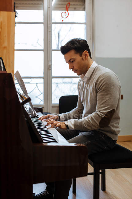 radical pistola delincuencia Hombre guapo tocando el piano durante el ensayo en el estudio de grabación  . — sonido, Entretenimiento - Stock Photo | #255844988