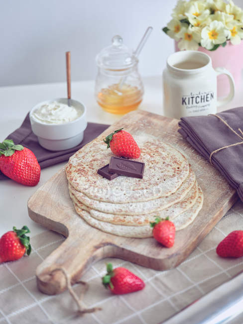 Frühstück mit Pfannkuchen und Erdbeeren auf Küchentisch mit Blumen — Stockfoto