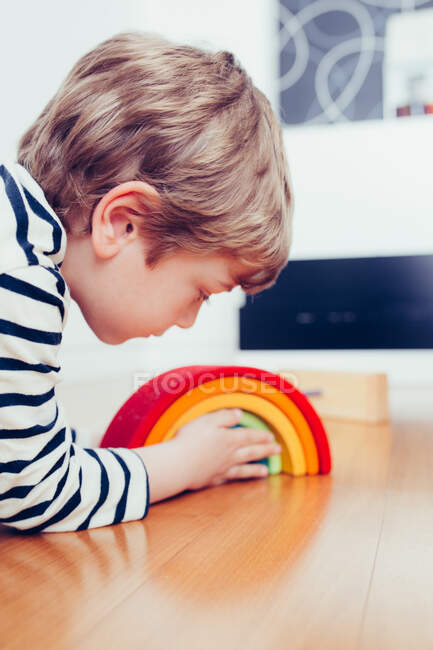 Blonde cute boy playing with waldorf rainbow puzzle — Stock Photo