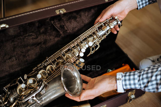 Обрезанный неузнаваемый мужчина, держащий саксофон из дела в студии — стоковое фото