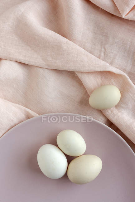 Weiße Eier auf einem Teller auf rosa Stoff serviert — Stockfoto
