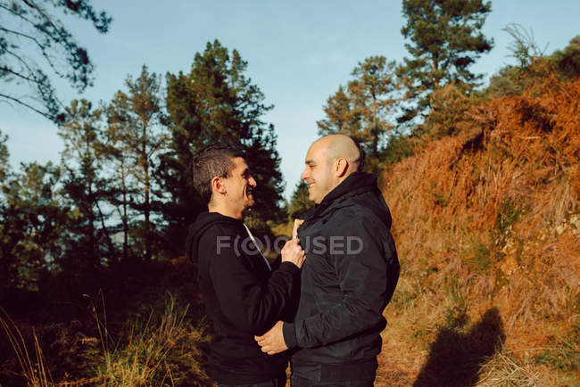 Felice coppia omosessuale abbraccio sul sentiero nella foresta nella giornata di sole — Foto stock