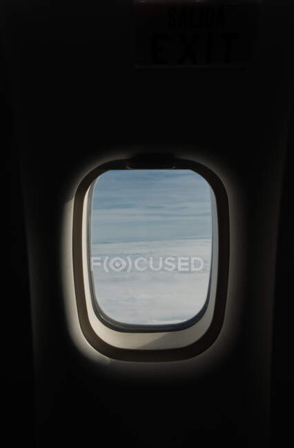 View of blue sky and thick clouds behind window of modern plane — Stock Photo