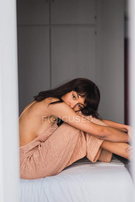 Молода жінка в оголеній сукні сидить на ліжку в спальні — стокове фото