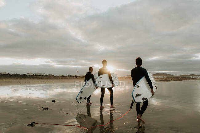 Люди з дошкою для серфінгу, що йдуть біля моря — стокове фото