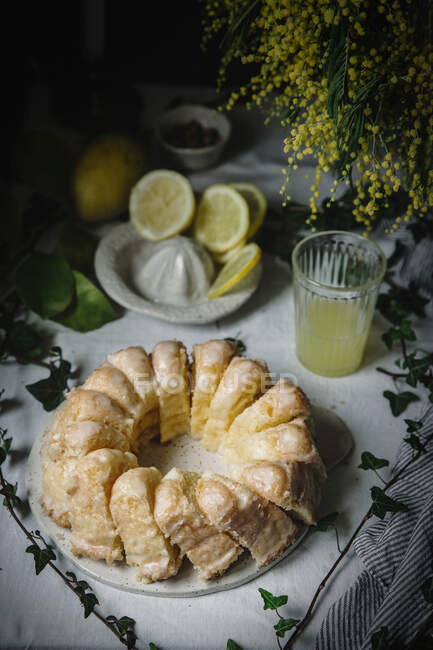 From above cut Bundt cake and glass of lemon juice on rustic table — Stock Photo