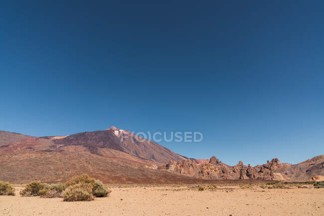 Tierra de arena cerca de la montaña Teide y pintoresca vista del cielo azul en Tenerife, Islas Canarias, España - foto de stock