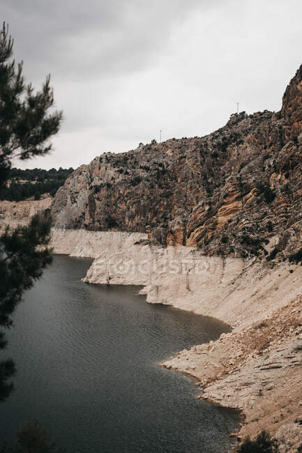 Pittoresca vista della ruvida scogliera rocciosa e dell'acqua tranquilla nella giornata nuvolosa in una campagna incredibile — Foto stock