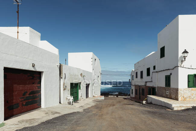 Schäbige Häuser in einer kleinen Straße der erstaunlichen Küstenstadt vor dem wogenden Meer und wolkenlosem blauen Himmel — Stockfoto