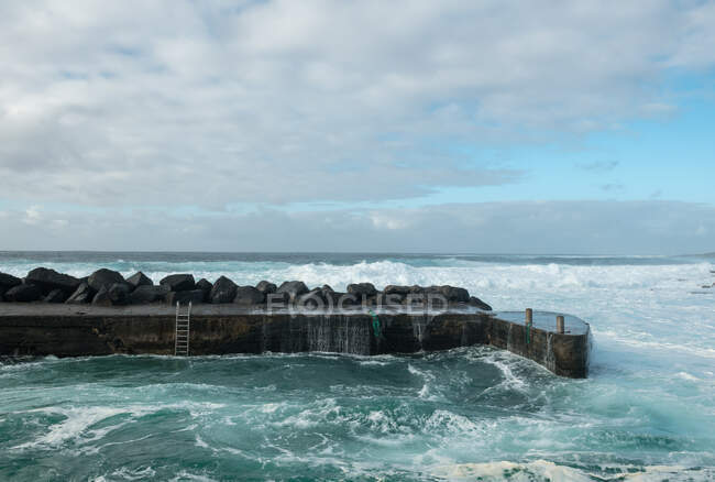 Морська хвиля біля кам'яного пірсу — стокове фото