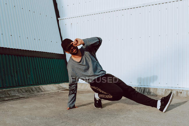 Cool guy break dancing near wall of modern building on city street — Stock Photo