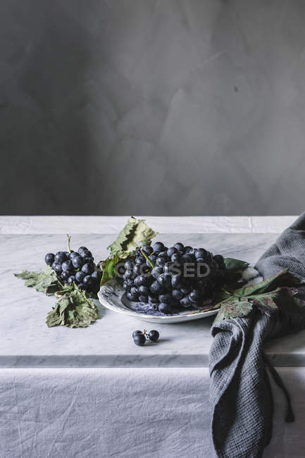 Куча свежего винограда на тарелке на столе — стоковое фото