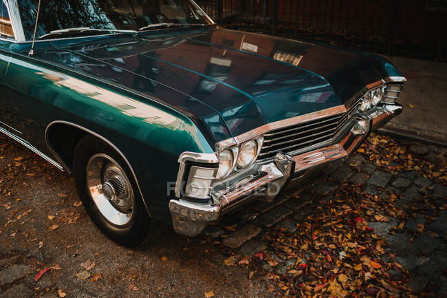 Ретро автомобиль темно-синего цвета с блестящим хромированным бампером, припаркованный на мощеной улице в опавших листьях, Нью-Йорк — стоковое фото